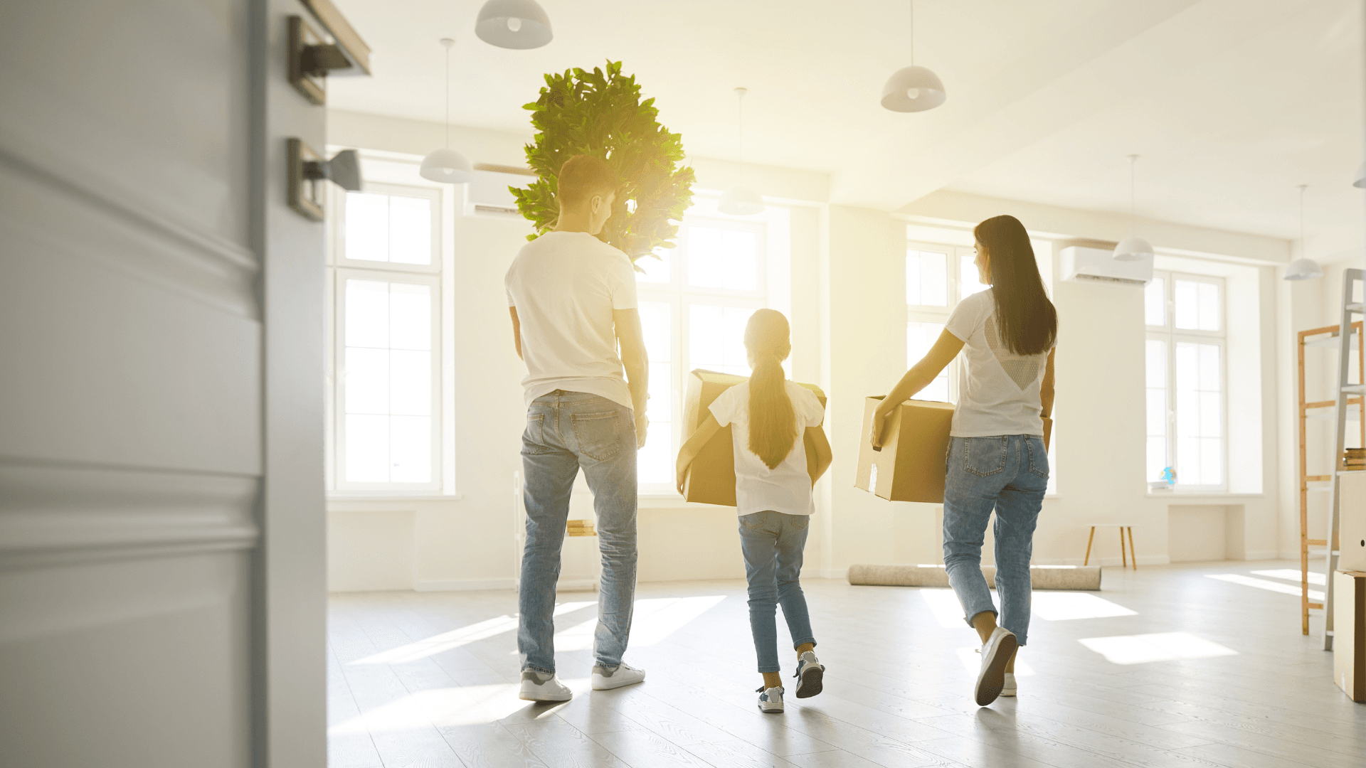 A family carrying boxes through a bright, empty new home