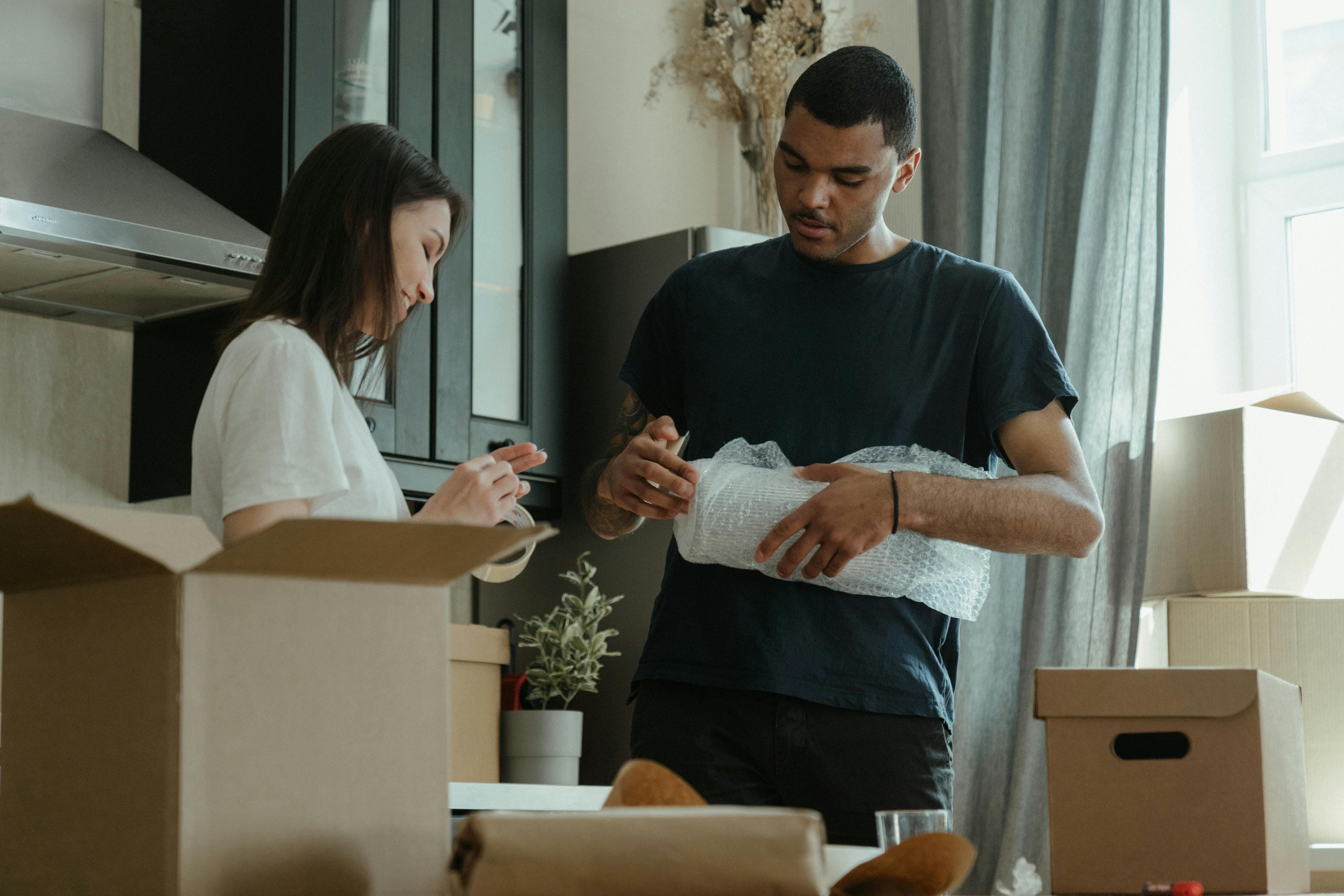 A couple carefully wrapping belongings into moving boxes