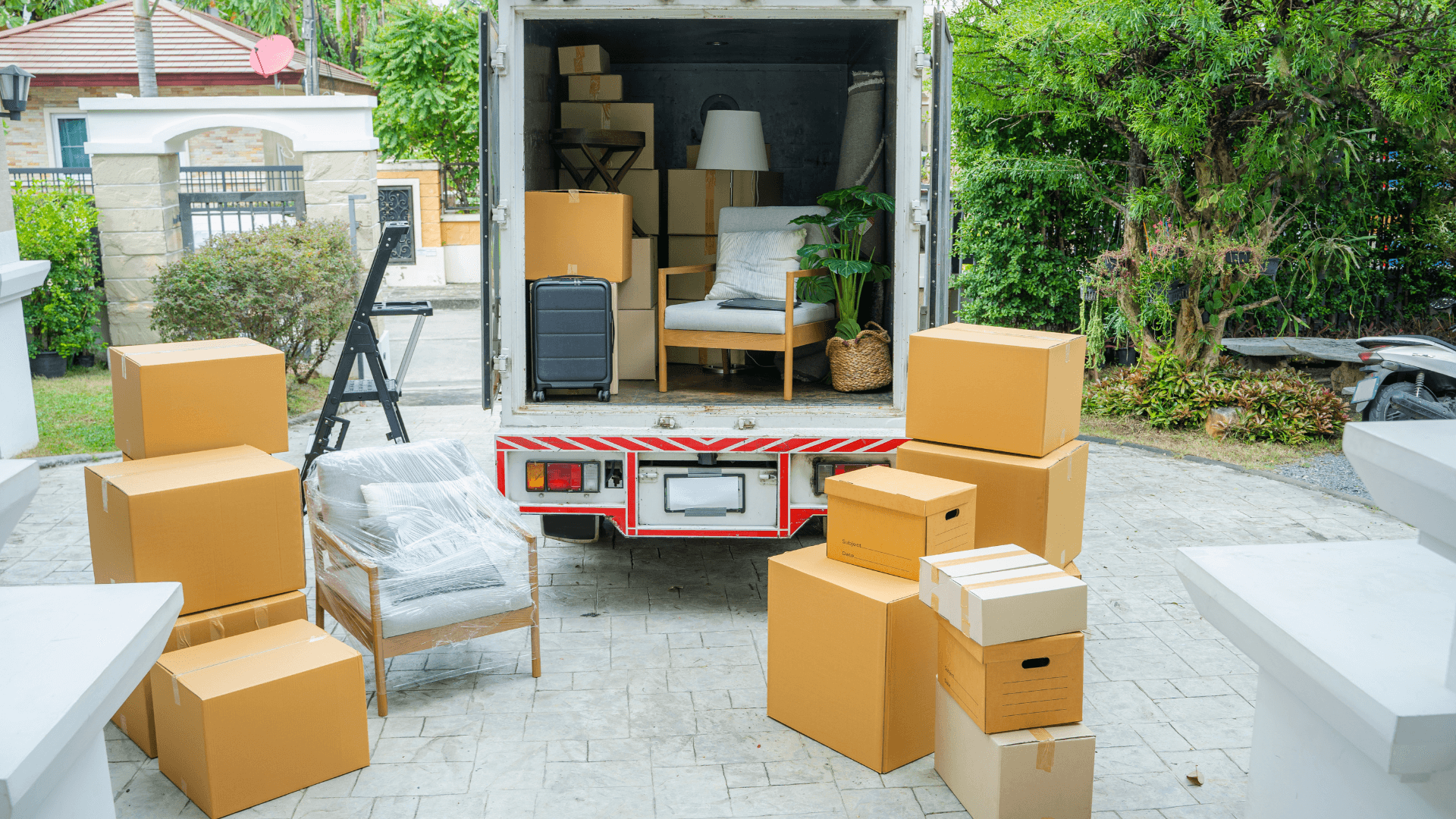 A garage and driveway packed with moving boxes and furniture