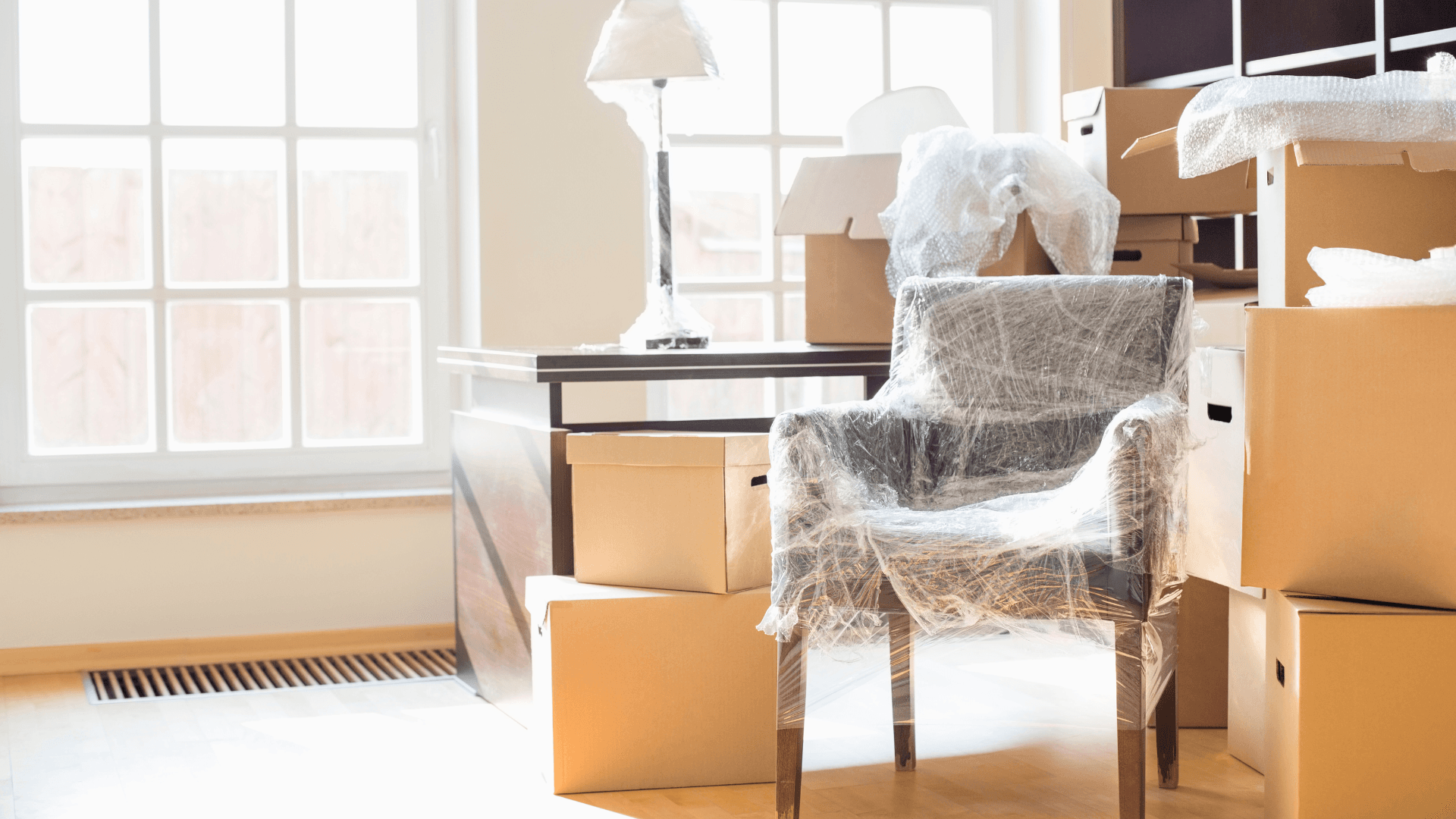 A chair wrapped in protective plastic beside packed moving boxes