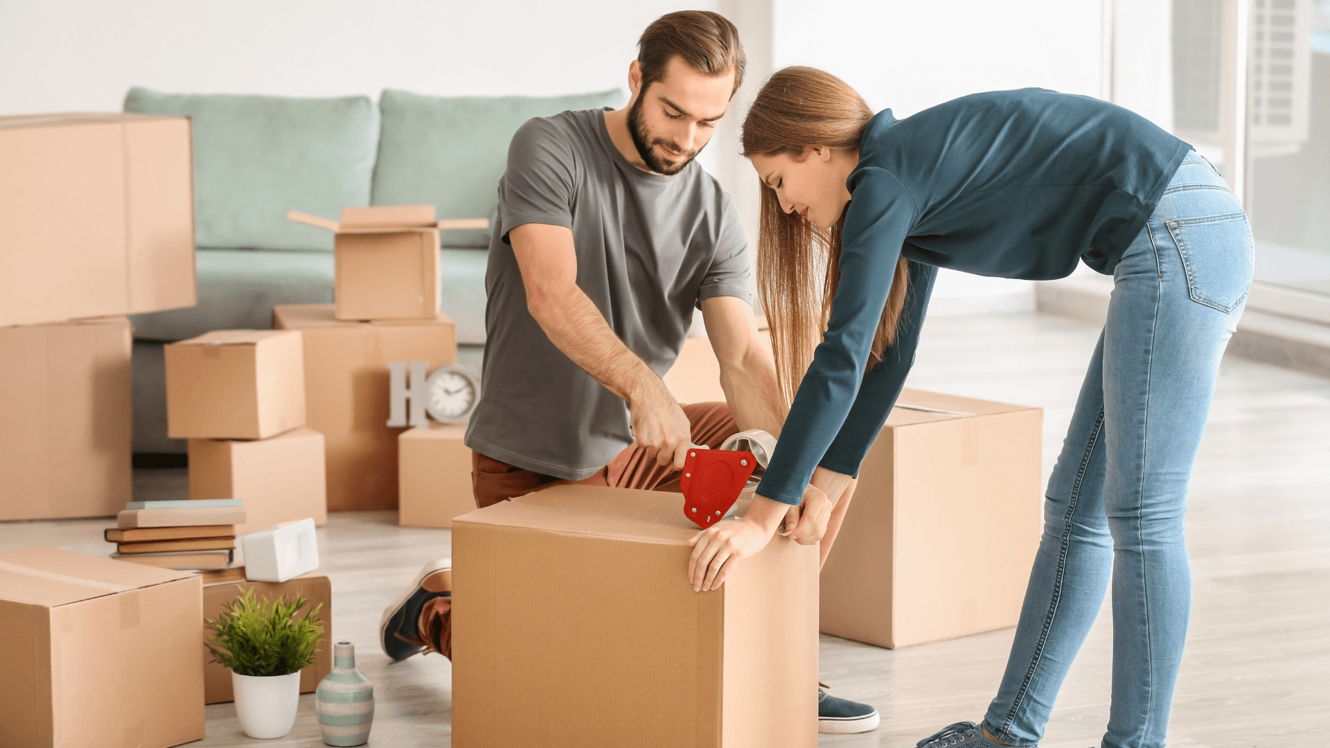 A couple taping up a moving box together
